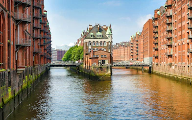 Speicherstadt canal view with historic brick warehouses in Hamburg, Elbphilharmonie in background.