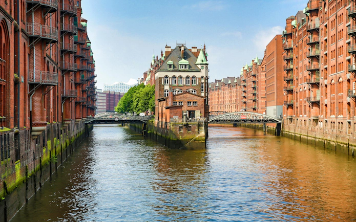 Speicherstadt canal view with historic brick warehouses in Hamburg, Elbphilharmonie in background.