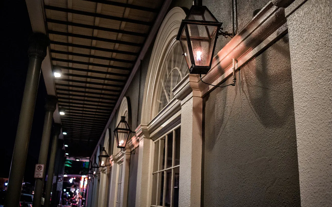 Historic New Orleans street with gas lanterns at night, part of the Ghosts and Spirits Walking Tour.