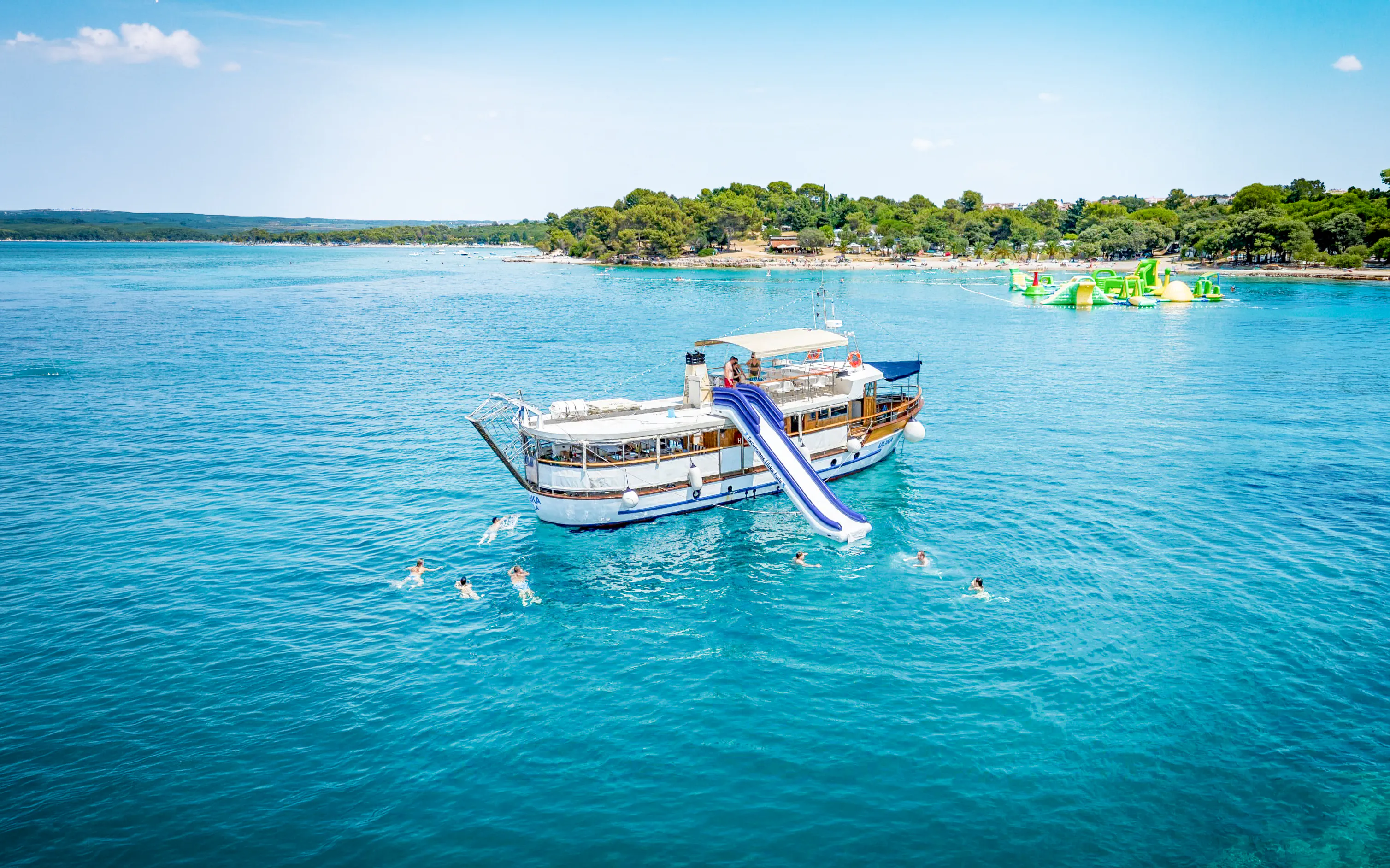 Boat with slide in Brijuni National Park, Croatia, surrounded by swimmers.