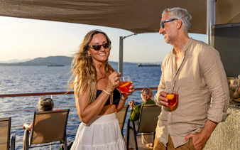 Guests enjoying drinks on Athens Day Cruise with sea view.