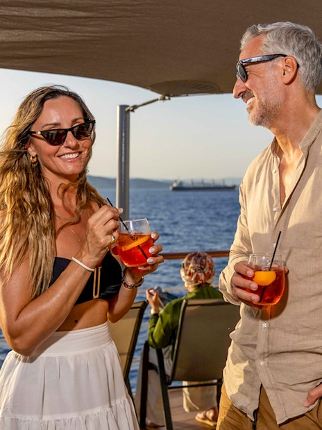 Guests enjoying drinks on Athens Day Cruise with sea view.