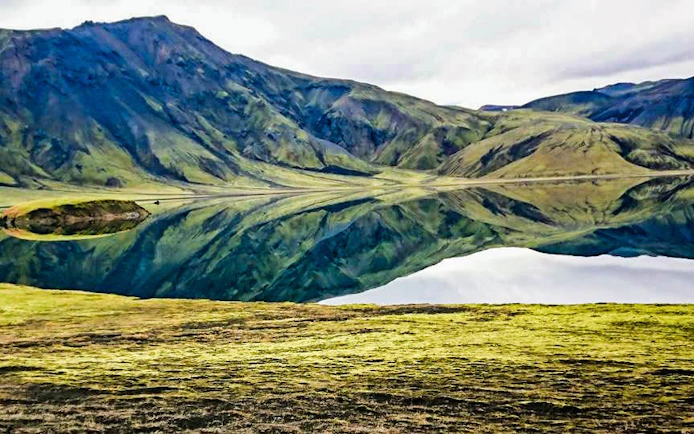 Landmannalaugar Highlands with mirrored mountains in a serene lake, Iceland.