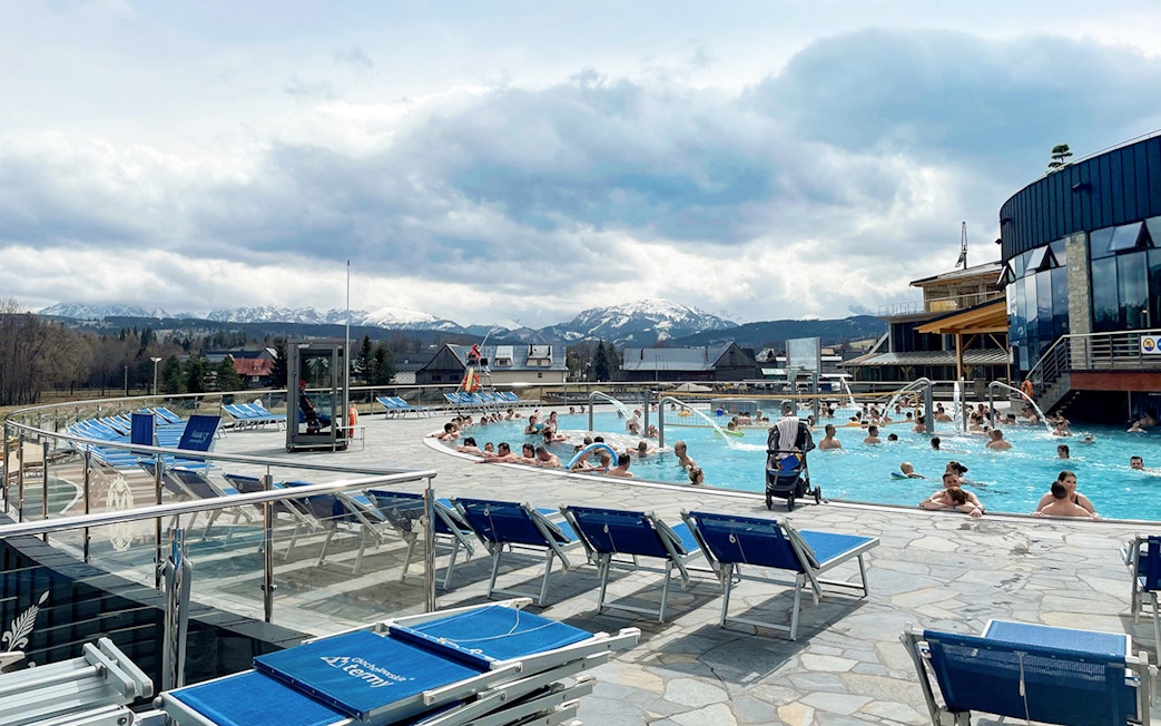 Visitors enjoying outdoor pools at Chocholowskie Thermal Bath with mountain views.