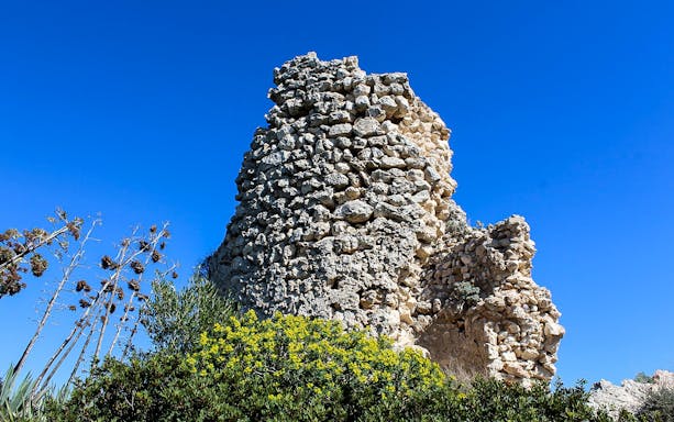 Ancient stone structure on Devil’s Saddle hike, surrounded by greenery under a clear blue sky.