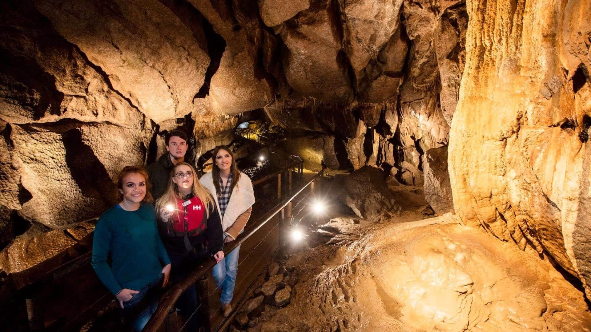 Tourists exploring illuminated Aillwee Cave in County Clare, Ireland.