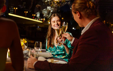 Seine River cruise dinner with people toasting champagne at night in Paris.
