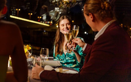 Seine River cruise dinner with people toasting champagne at night in Paris.