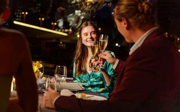 Seine River cruise dinner with people toasting champagne at night in Paris.