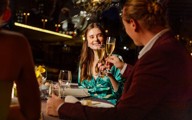 Seine River cruise dinner with people toasting champagne at night in Paris.