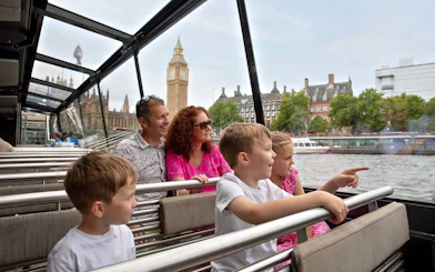 Family enjoying a London HOHO cruise with view of Big Ben and the Thames.