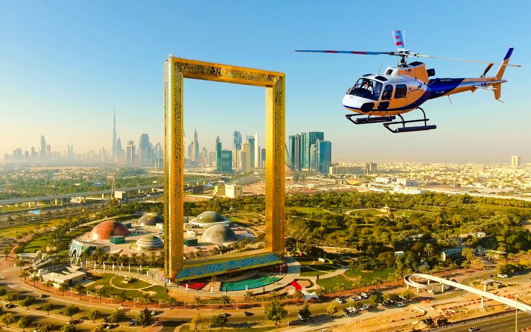 Helicopter flying above Dubai Frame with city skyline in the background.