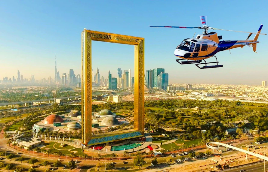 Helicopter flying above Dubai Frame with city skyline in the background.