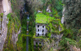 Ancient mill ruins covered in greenery in Sorrento, part of a guided tour from Naples.