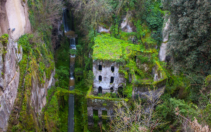 Ancient mill ruins covered in greenery in Sorrento, part of a guided tour from Naples.