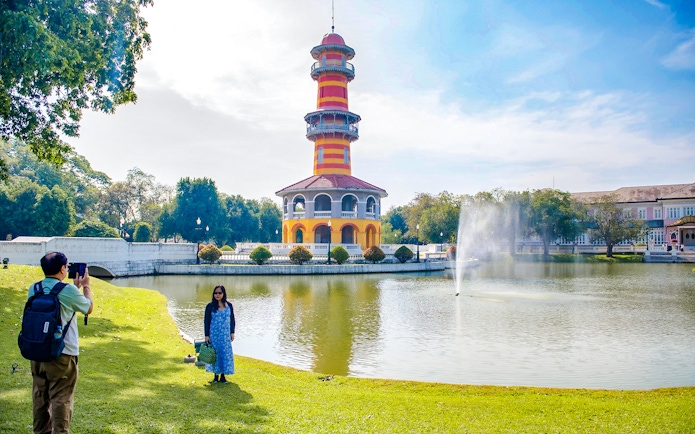 Ho Withun Thasana tower by a pond at Bang Pa-In Summer Palace, Ayutthaya, with visitors taking photos.