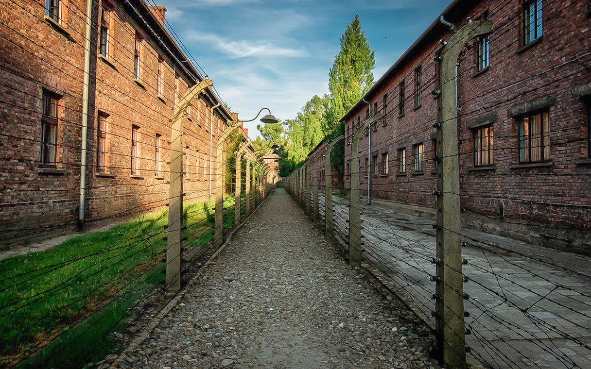 Pathway between brick buildings and barbed wire fences at Auschwitz, Poland.