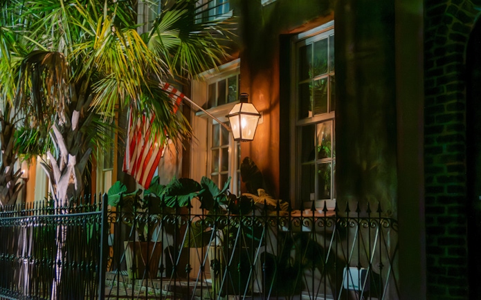 Historic Charleston house with lantern and American flag at night.
