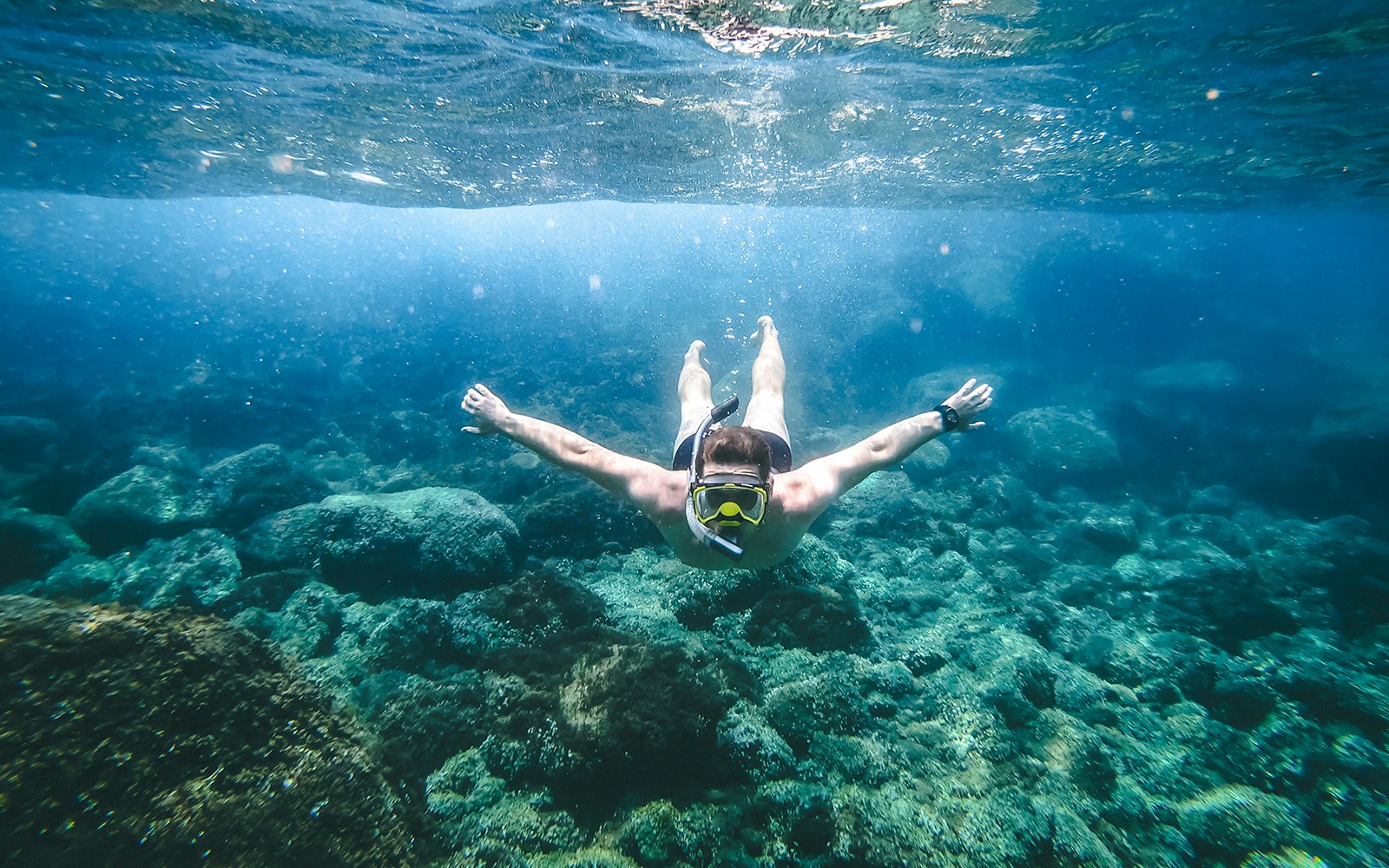 A male tourist snorkeling in the blue waters of Caldera