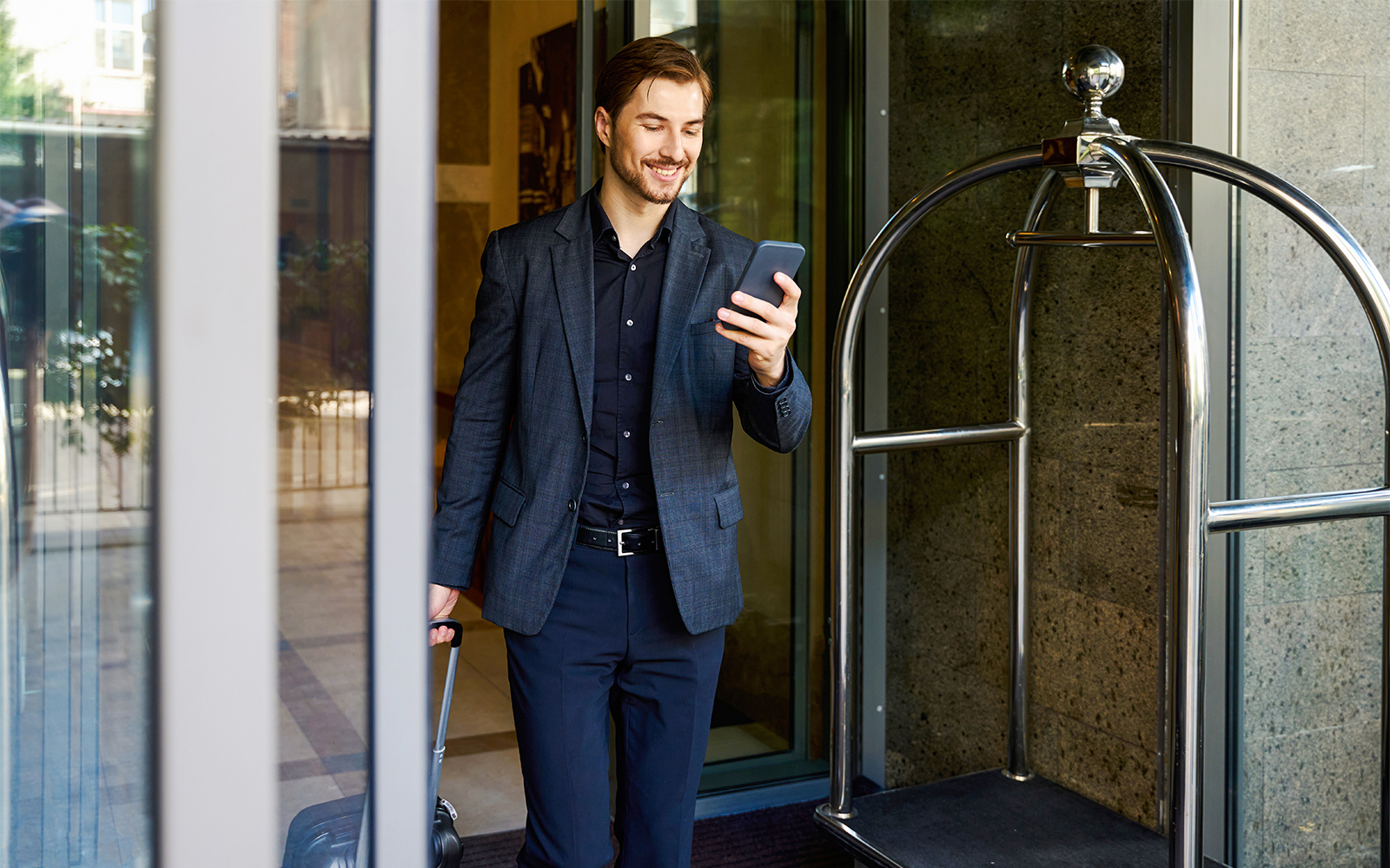 Young businessman checking smartphone while exiting Grand Hyatt Melbourne.