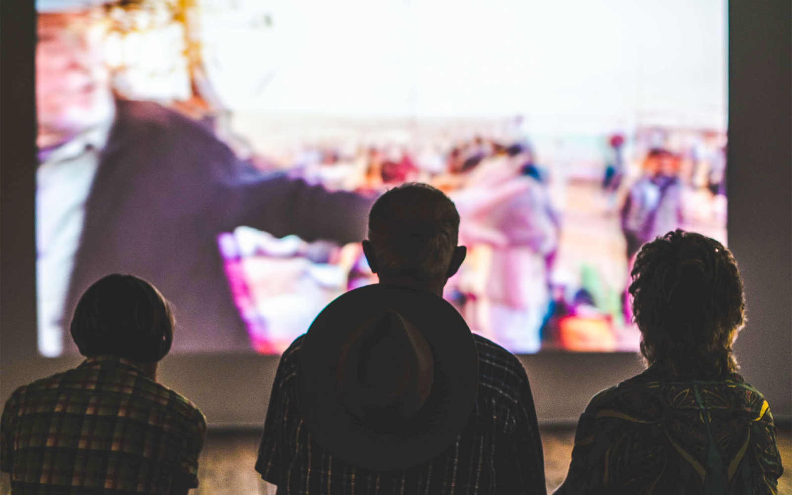 Outdoor cinema setup at Kew Gardens, Royal Botanic Gardens, with people seated on the lawn.