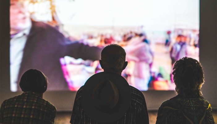 Outdoor cinema setup at Kew Gardens, Royal Botanic Gardens, with people seated on the lawn.
