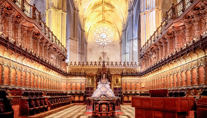 Seville Cathedral interior with ornate Gothic arches and intricate stained glass windows.
