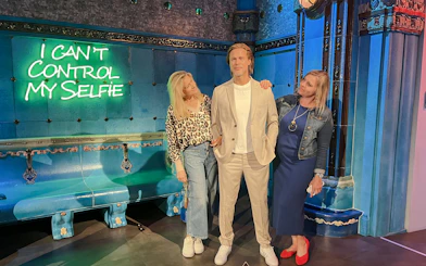 Wax figure at Madame Tussauds Budapest with visitors posing for photos.