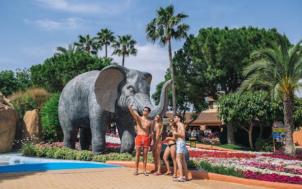Friends taking a selfie by elephant statue at Aqualand Costa Adeje, Tenerife.