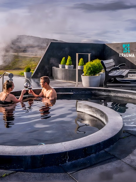 Couple enjoying Krauma Geothermal Baths in Iceland with steam rising in the background.
