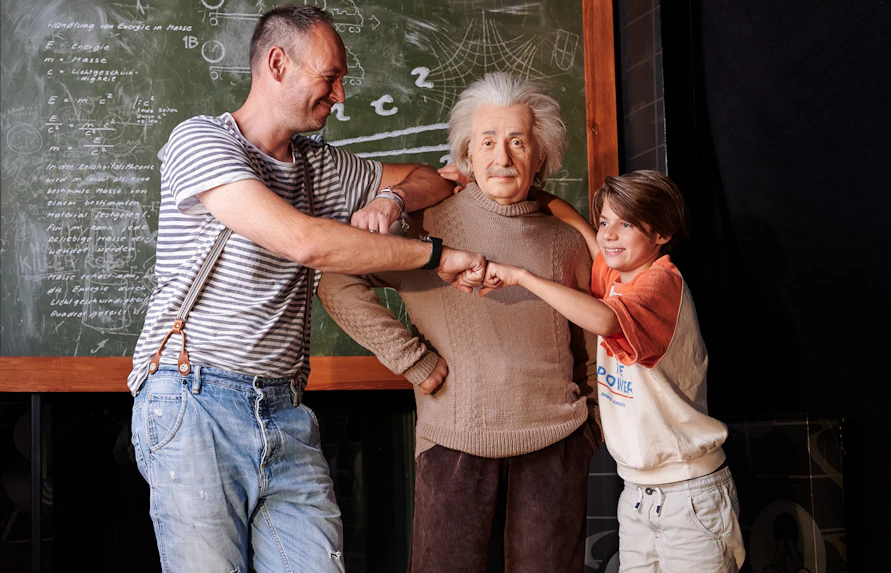 Visitors posing with Albert Einstein wax figure at Madame Tussauds Berlin.