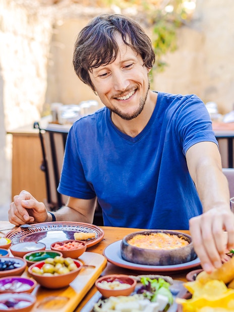 Man enjoying Turkish breakfast with various dishes and tea.