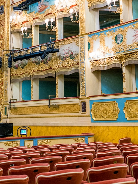 Teatro La Fenice auditorium with ornate balconies and red seats, Venice.