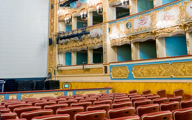 Teatro La Fenice auditorium with ornate balconies and red seats, Venice.