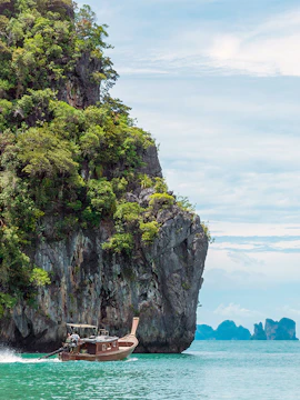 Longtail boat near limestone cliffs in Phang Nga Bay, Thailand.