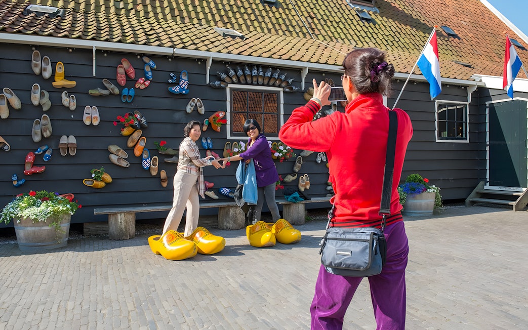 Guide photographing guests in front of a wooden shoe display during Keukenhof Windmills Tour.