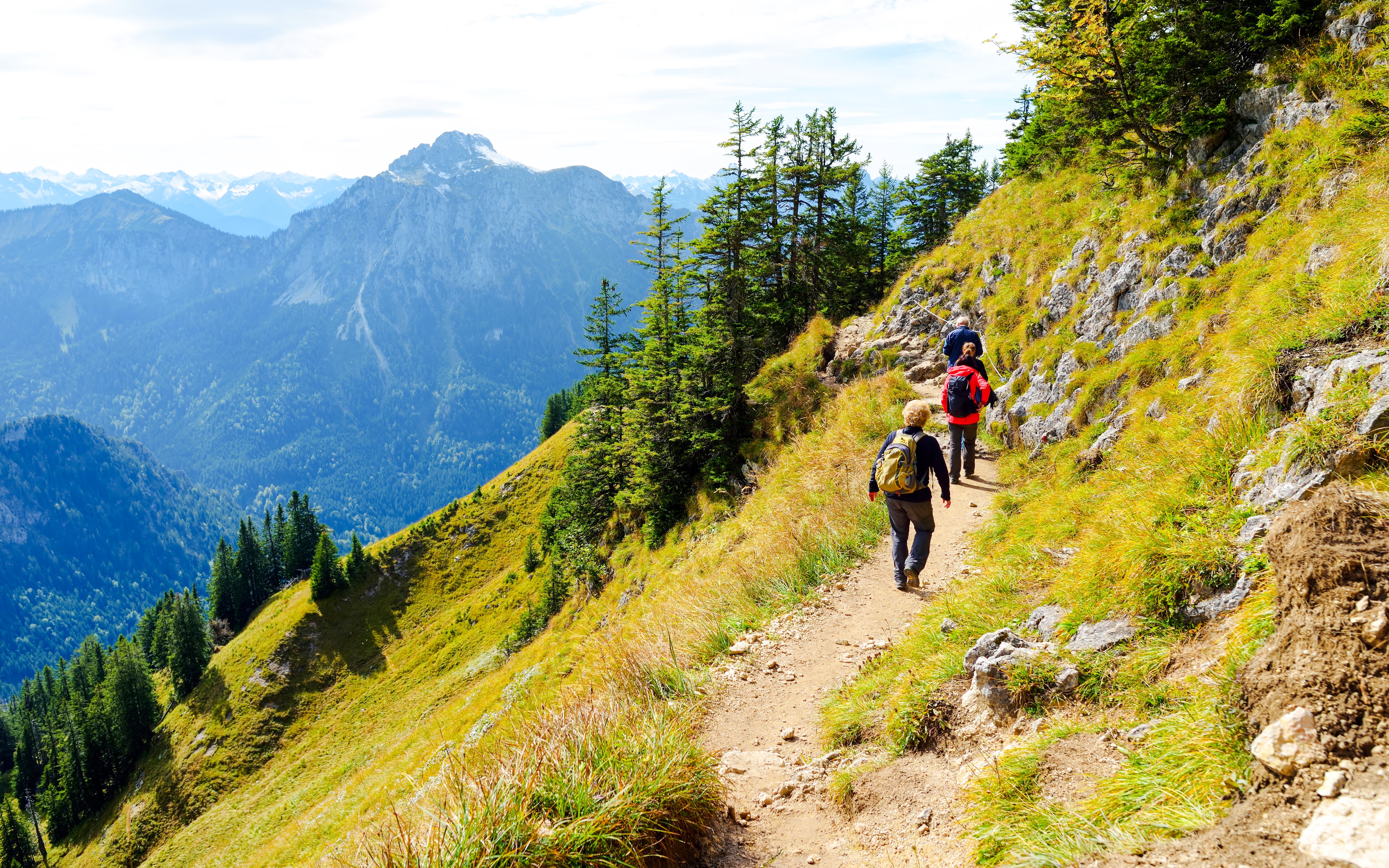 Hikers on a trail with Tegelberg Mountain in the background during the Tegelberg Mountain Festival.