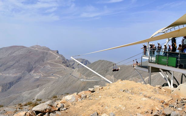 Visitors ziplining at Jebel Jais, UAE, with mountain views in the background.