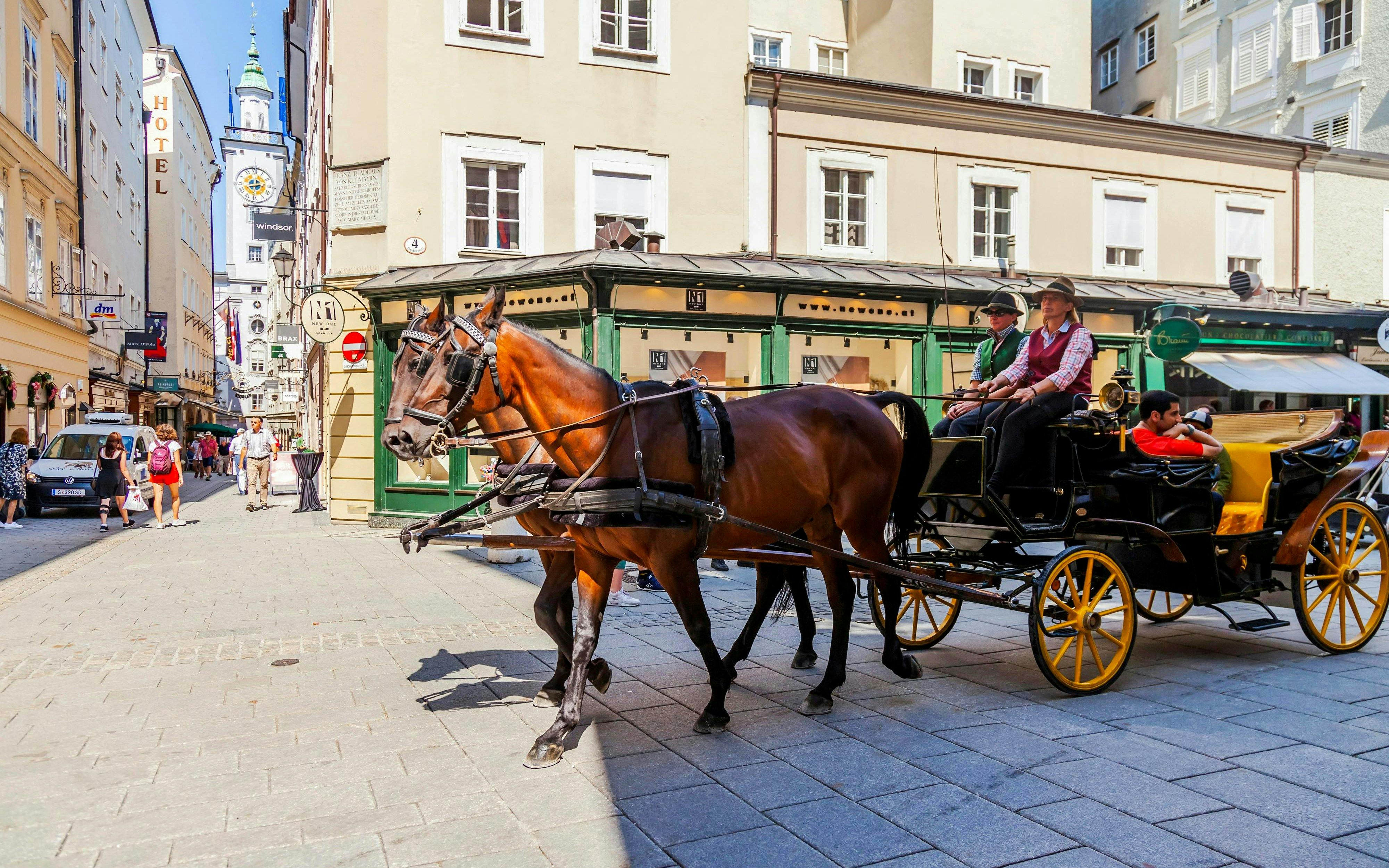 Horse-drawn carriage on a street in Salzburg, Austria, with historic buildings in the background.