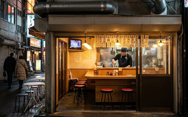 Chef preparing food in a cozy Osaka street restaurant during the night foodie tour.