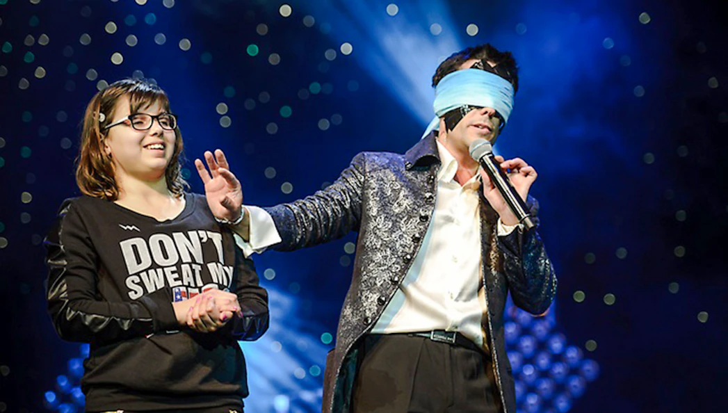 Performer with blindfold and audience member on stage at Frederick Da Silva Vegas show.