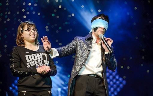 Performer with blindfold and audience member on stage at Frederick Da Silva Vegas show.