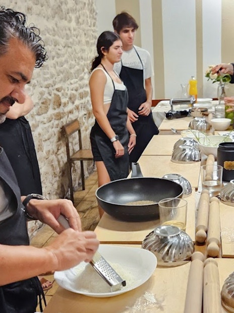 Participants in a Rome cooking class preparing dishes at a kitchen counter.