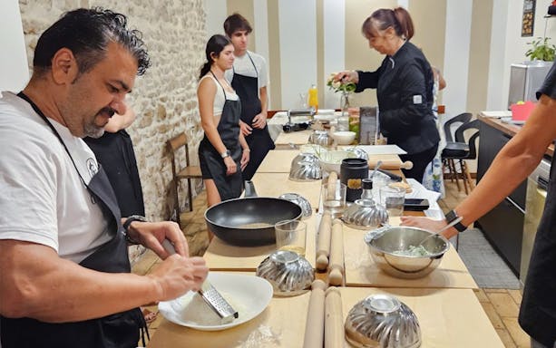 Participants in a Rome cooking class preparing dishes at a kitchen counter.