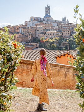 Woman walking towards Siena Cathedral in Tuscany, Italy, surrounded by historic buildings.