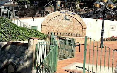 Benalmádena Pueblo fountain with stone arch and greenery, part of self-guided city exploration game.