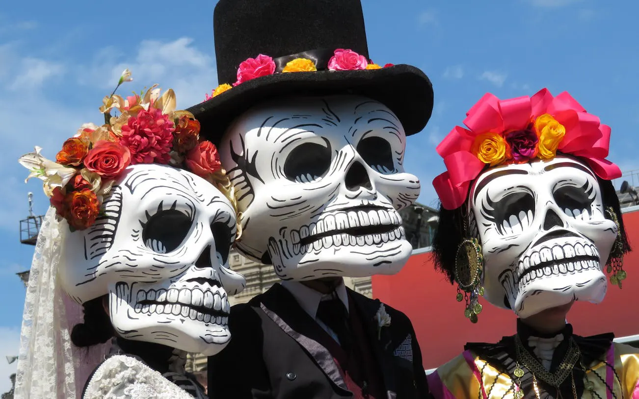 People in traditional Day of the Dead costumes with skull masks at Mixquic celebration.