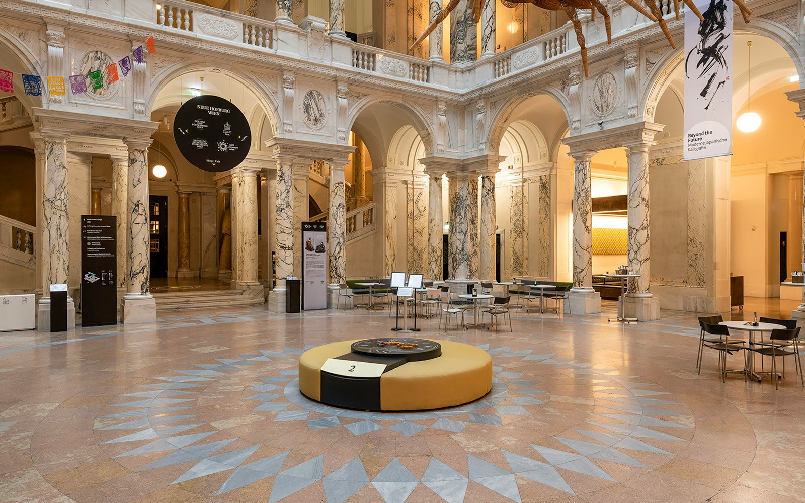 Inside view of the New Hofburg Palace with marble columns and seating area.