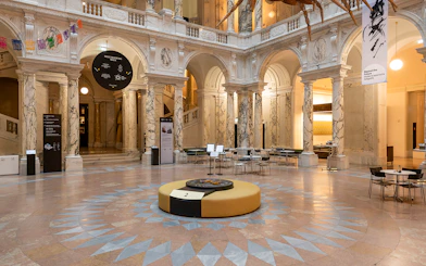 Inside view of the New Hofburg Palace with marble columns and seating area.