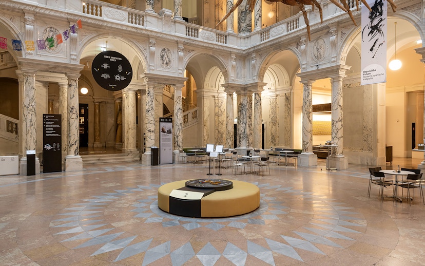 Inside view of the New Hofburg Palace with marble columns and seating area.